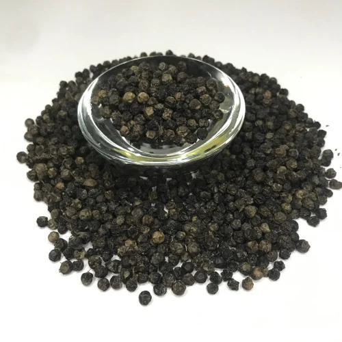 Close-up of shiny, wrinkly whole black peppercorns, showing their rich texture and dark color.