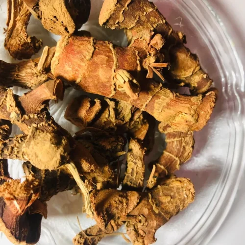 Close-up of dried, pale brown Araththa Root (Alpinia Calcarata) pieces, showing their fibrous texture and aromatic surface.