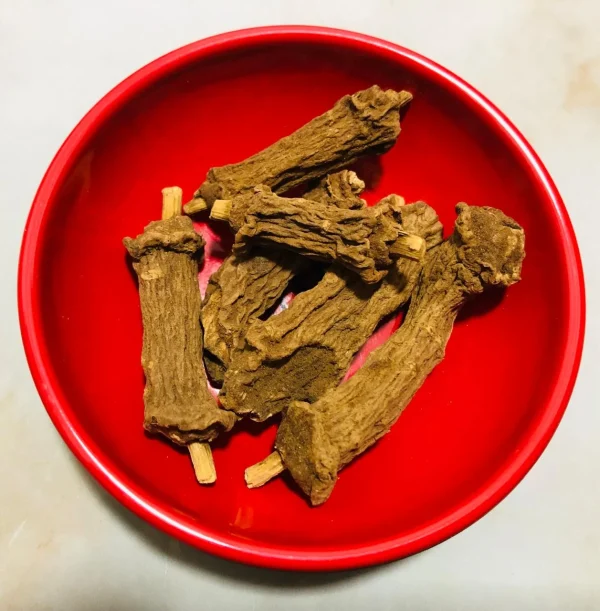 Dried Iramusu pieces steeping in cold or warm water in a clear glass pitcher or traditional clay pot, preparing a refreshing herbal drink.