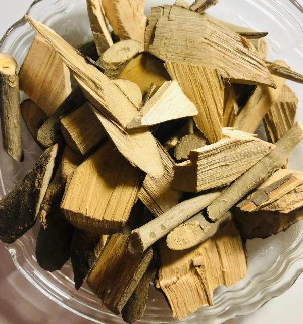 Dried Pawatta Root pieces simmering in water in a traditional pot or a glass, preparing a herbal decoction.