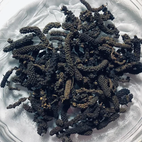 Close-up of elongated, cylindrical, dried Thippili (Long Pepper) spikes, showing their textured surface.